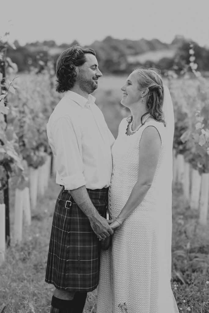 A bride and groom smiling in a vineyard